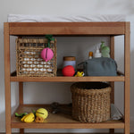 The Oli & Carol natural rubber pacifier holders are on a changing table with other baby changing items