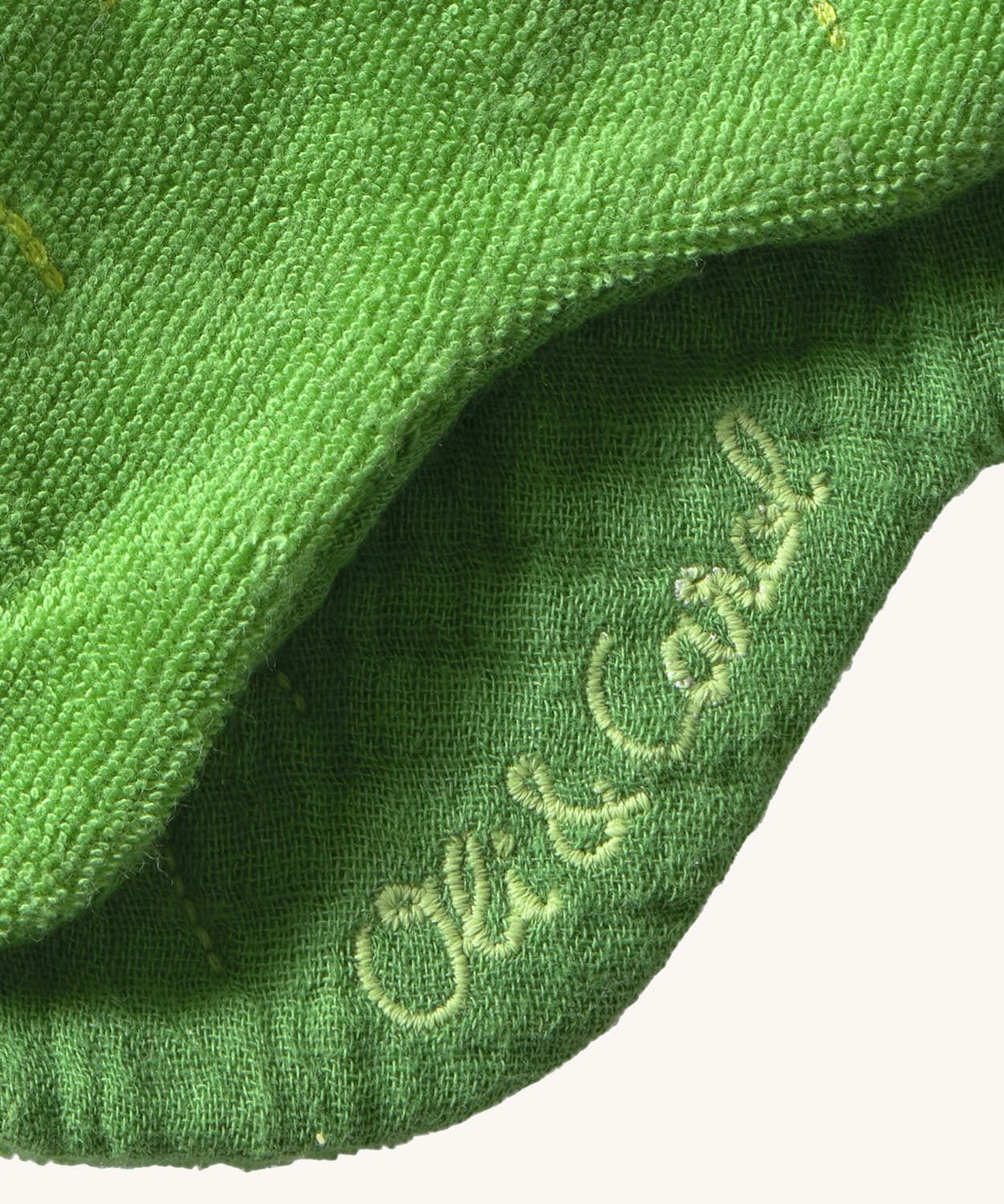 A close up of the  Oli & Carol Kendall the kale baby bib available at Babipur showing the brand name stitch detail on the inside of the bib