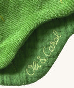 A close up of the  Oli & Carol Kendall the kale baby bib available at Babipur showing the brand name stitch detail on the inside of the bib