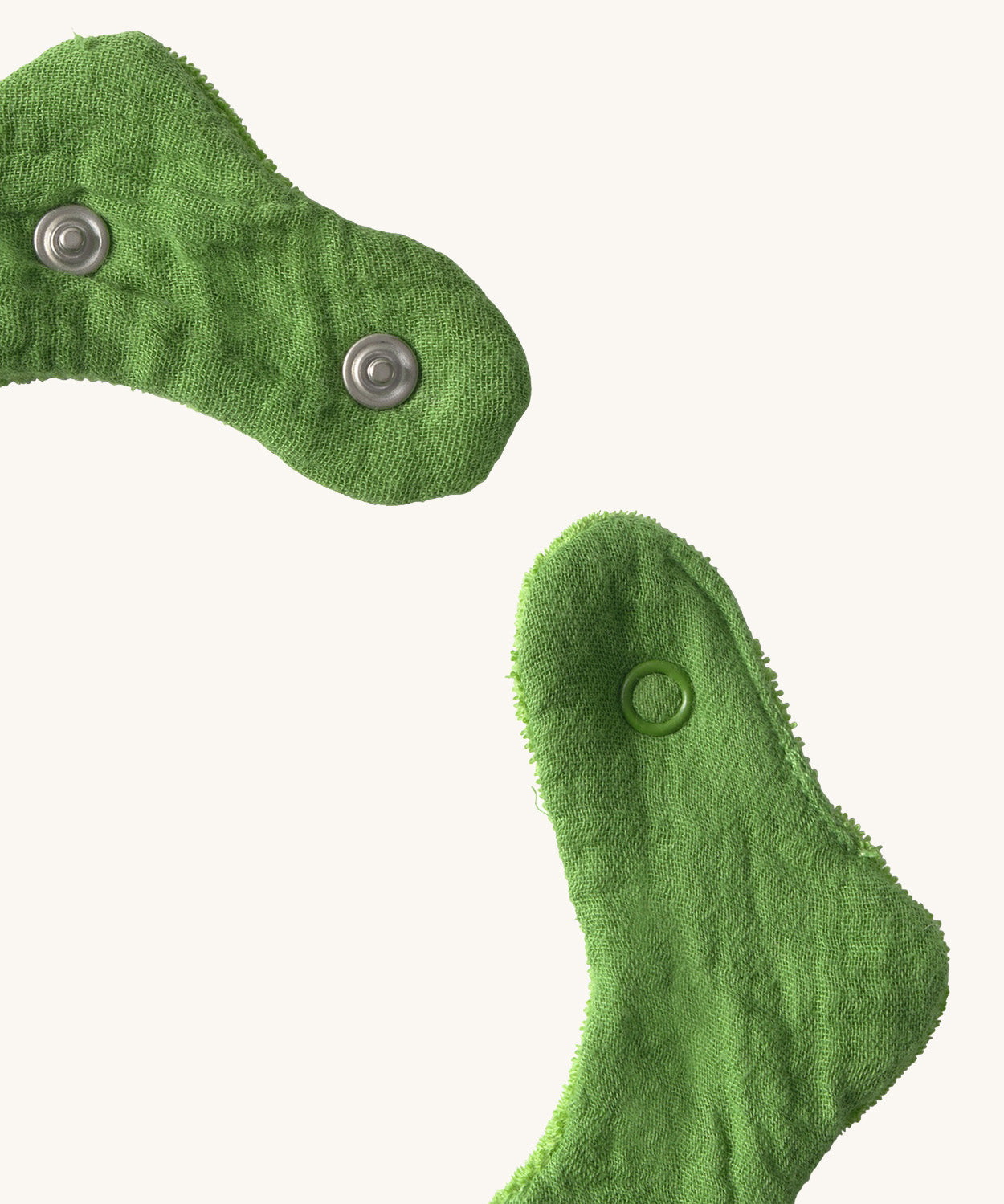 A close up of the  Oli & Carol Kendall the kale baby bib available at Babipur showing the popper fastener for size adjustment. 