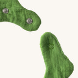 A close up of the  Oli & Carol Kendall the kale baby bib available at Babipur showing the popper fastener for size adjustment. 