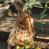 A child sitting on a stone surface next to the Oli & Carol wooden kale plate filled with vegetables available at Babipur.