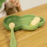 A close up of the Oli & Carol wooden leek spoon from the kale and leek set resting on a kale plate available at Babipur.