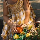 A close up of a child in a garden and putting different food items on a Oli & Carol Kendall the Kale plate available at Babipur.