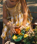 A close up of a child in a garden and putting different food items on a Oli & Carol Kendall the Kale plate available at Babipur.