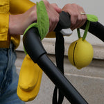 A closer look at the Lemon and Banana Pacifier Holder and Teething Toy, which have been tied onto a pram handle using the muslin cloth leaves on the top of the holder.