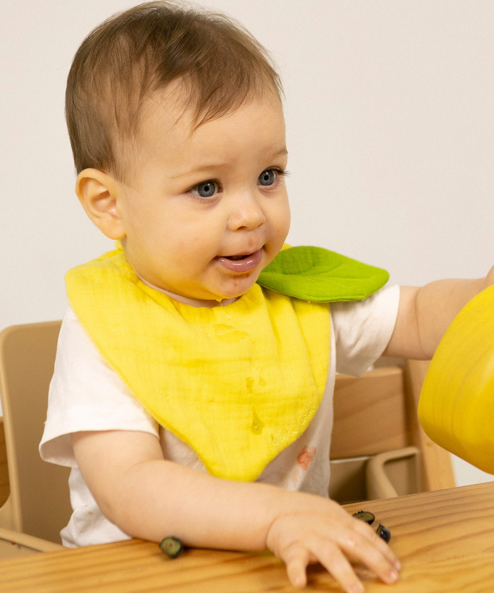 Baby wearing an organic cotton lemon feeding bib, by Oli and Carol, for sale at Babipur.