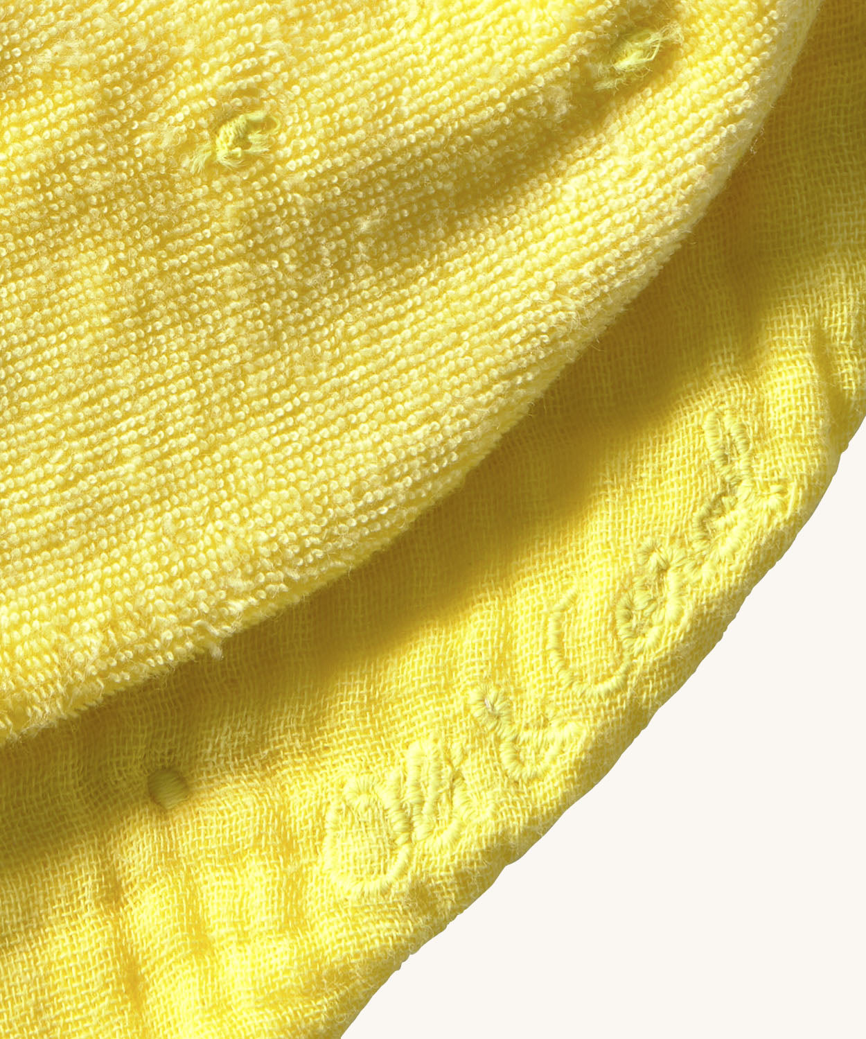 A close up of the  Oli & Carol Lou the lemon baby bib available at Babipur showing the brand name stitch detail on the inside of the bib