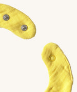 A close up of the  Oli & Carol Lou the lemon baby bib available at Babipur showing the popper fastener for size adjustment. 