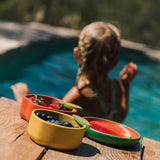 A child in a swimming pool with the Oli & Carol lemon bowl on the side filled with fruit available at Babipur.