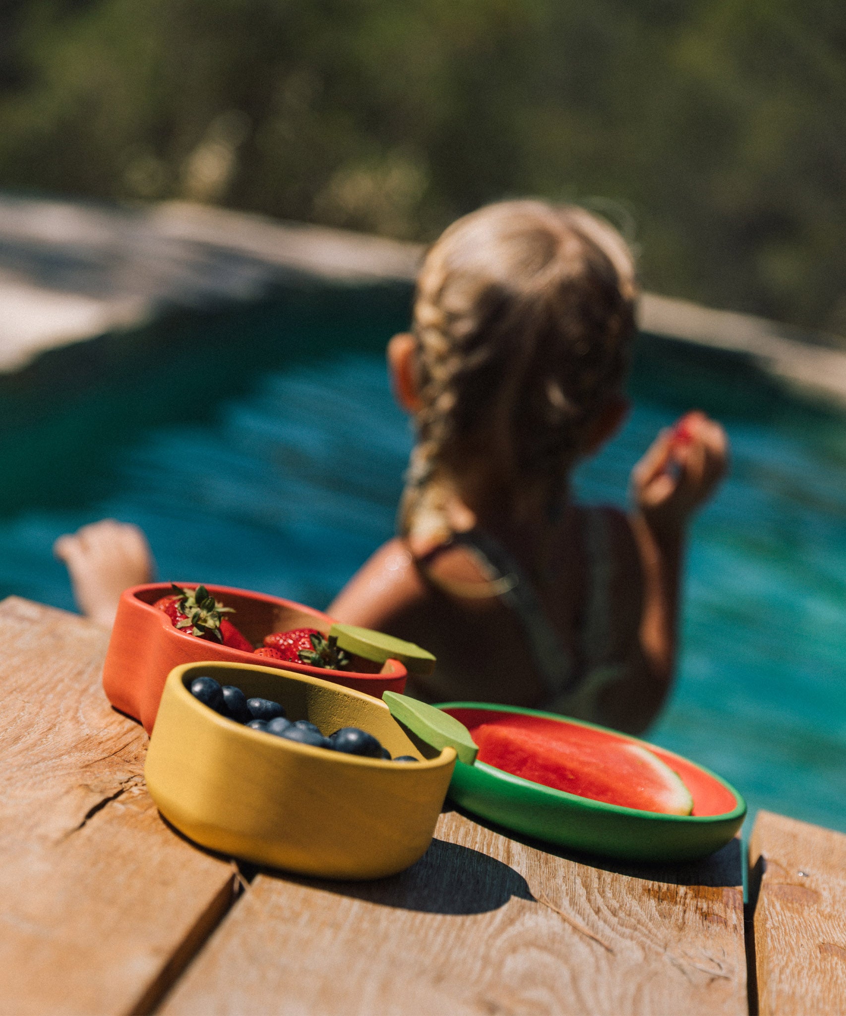 A child in a swimming pool with the Oli & Carol lemon bowl on the side filled with fruit available at Babipur.