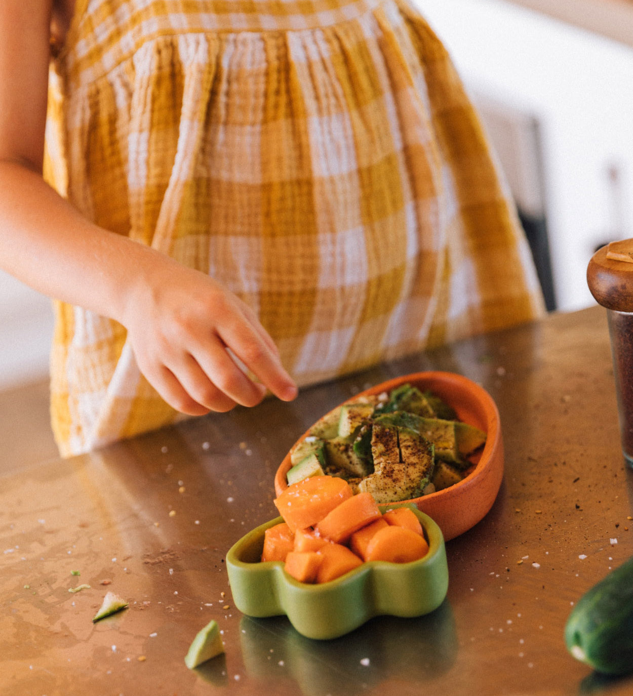 A child standing over the Oli & Carol Cathy the carrot wooden plate and spoon set with food. Set available at Babipur.