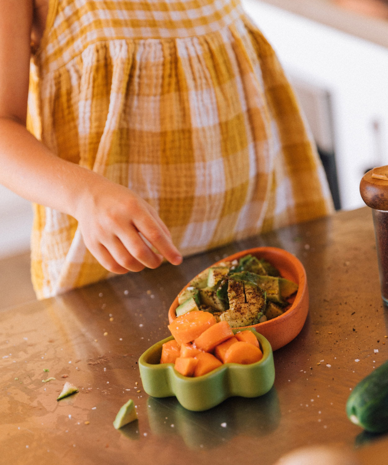 A child standing over the Oli & Carol Cathy the carrot wooden plate and spoon set with food. Set available at Babipur.