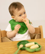 A child eating a banana from the Oli & Carol Kendall the Kale wooden plate and spoon set available at Babipur. 