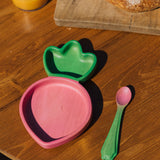 A close up of the Oli & Carol Ramona the radish wooden plate and spoon set available at Babipur on a wooden surface