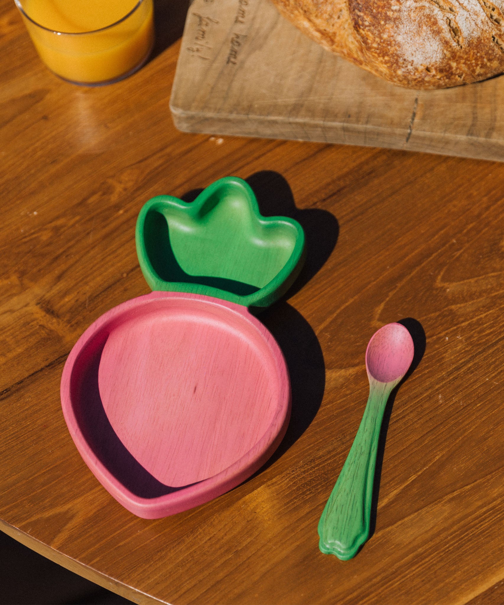 A close up of the Oli & Carol Ramona the radish wooden plate and spoon set available at Babipur on a wooden surface