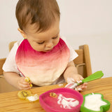 A child eating fruit and yogurt from the Oli & Carol Ramona Radish wooden plate and spoon set available at Babipur. 