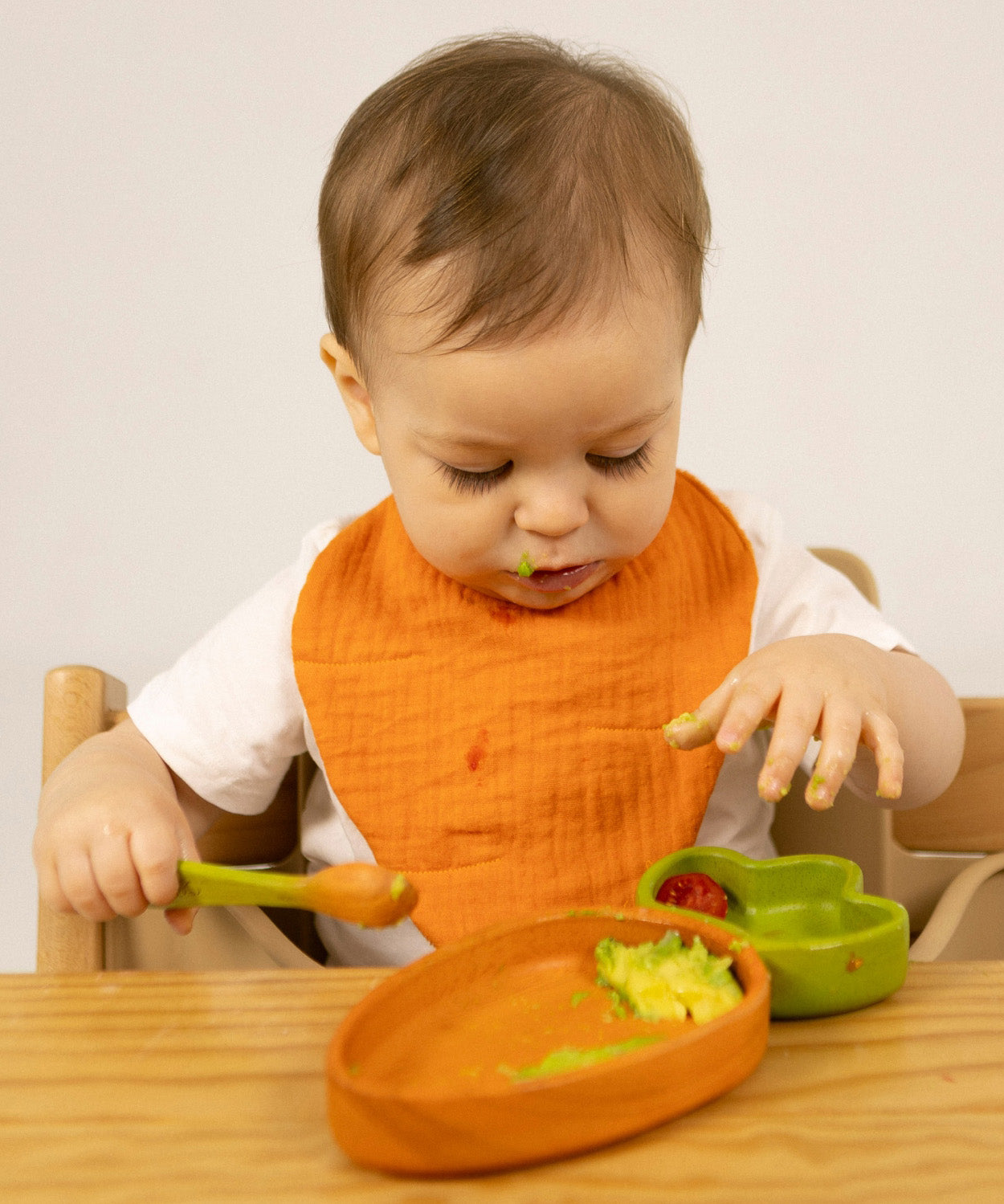 A child eating from the Oli & Carol Cathy the carrot wooden plate and spoon set available at Babipur.