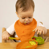 A child eating from the Oli & Carol Cathy the carrot wooden plate and spoon set available at Babipur.