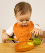 A child eating from the Oli & Carol Cathy the carrot wooden plate and spoon set available at Babipur.