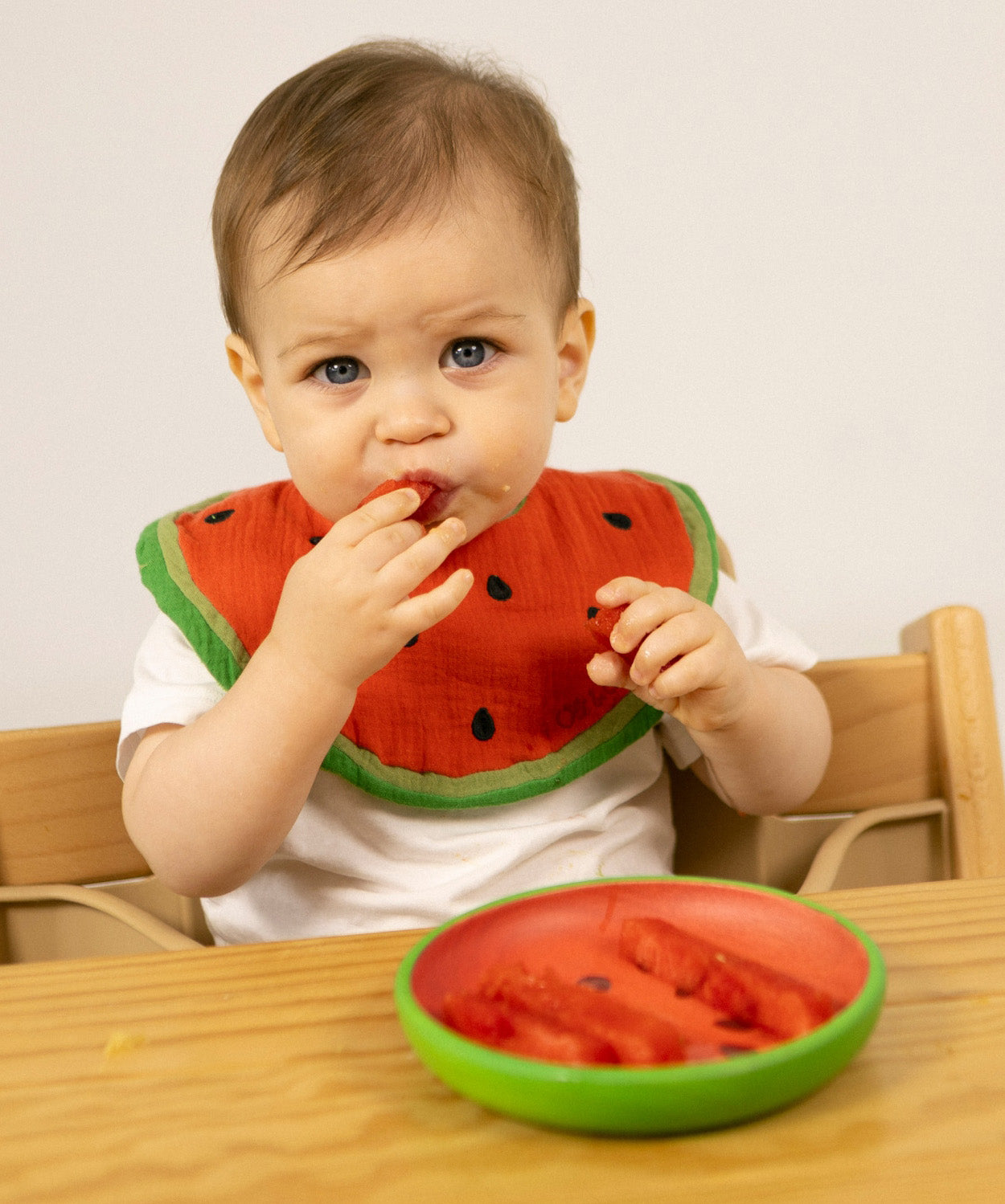 A child eating watermelon from the Oli & Carol Wally the watermelon wooden plate and spoon set available at Babipur. 