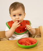 A child eating watermelon from the Oli & Carol Wally the watermelon wooden plate and spoon set available at Babipur. 