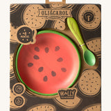 A close up of the cardboard packaging holding the Oli & Carol Wally the watermelon wooden plate and spoon set available at Babipur. 
