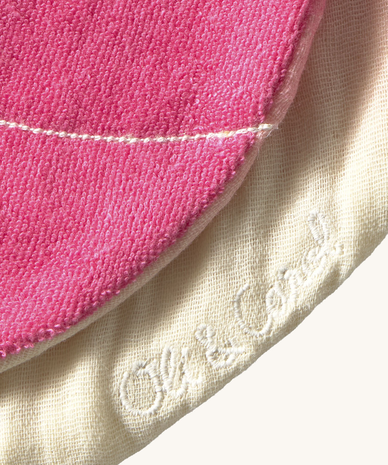 A close up of the  Oli & Carol Ramona the radish baby bib available at Babipur showing the brand name stitch detail on the inside of the bib