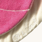 A close up of the  Oli & Carol Ramona the radish baby bib available at Babipur showing the brand name stitch detail on the inside of the bib