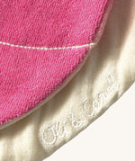 A close up of the  Oli & Carol Ramona the radish baby bib available at Babipur showing the brand name stitch detail on the inside of the bib