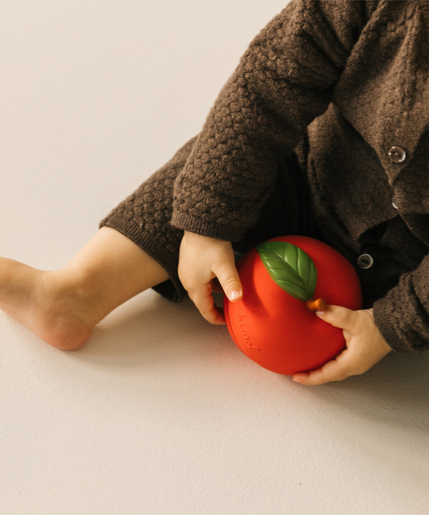 A baby playing with the Oli & Carol red apple stacking toy rattle ball available at Babipur. 