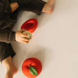 A top down photo of a baby playing with the core from the Oli & Carol red apple stacking toy rattle ball available at Babipur. 