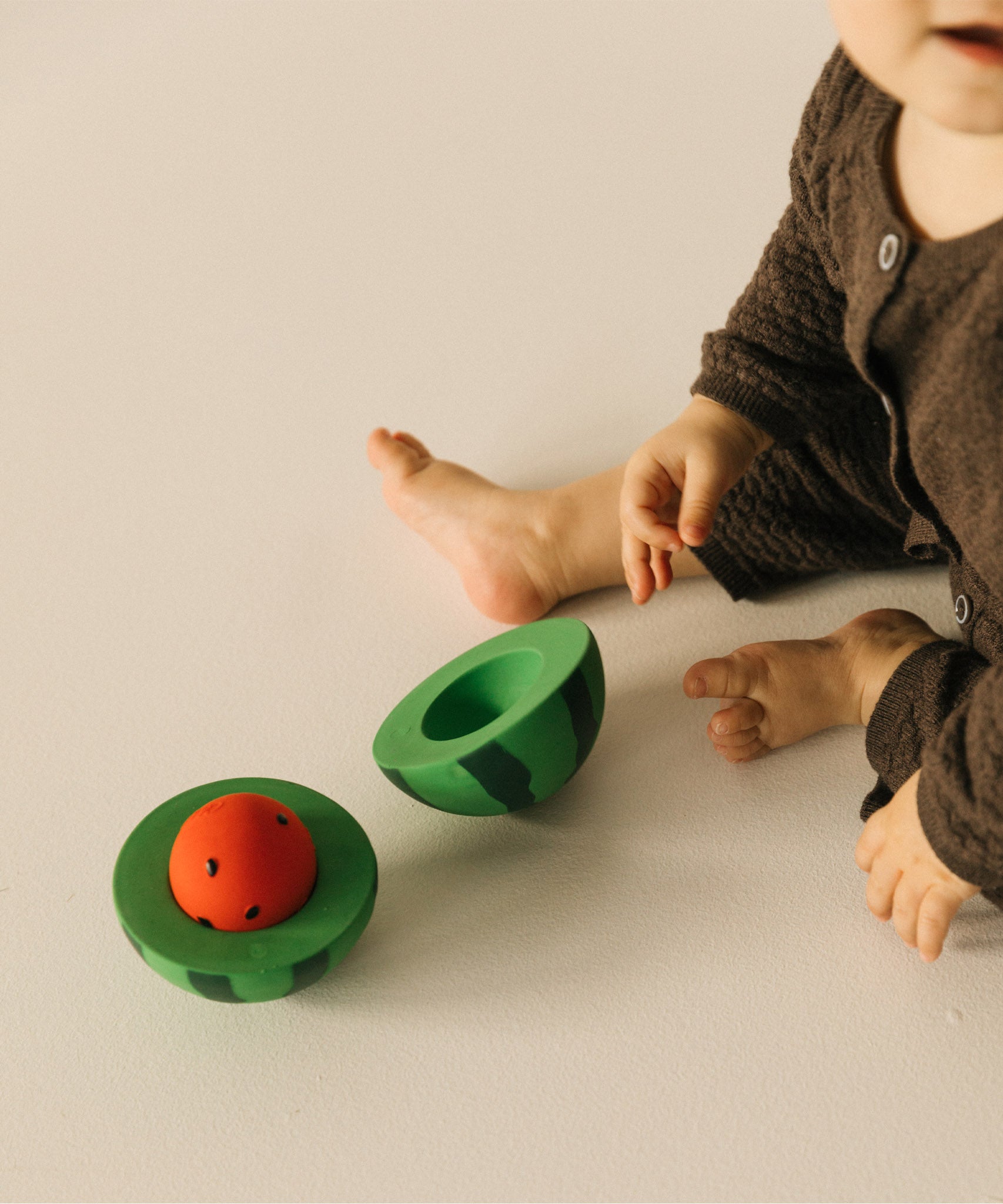 A child with a open watermelon Oli & Carol toy rattle available at Babipur