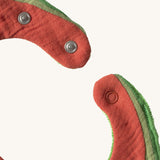 A close up of the  Oli & Carol Wally the watermelon baby bib available at Babipur showing the popper fastener for size adjustment. 