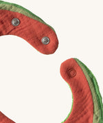 A close up of the  Oli & Carol Wally the watermelon baby bib available at Babipur showing the popper fastener for size adjustment. 