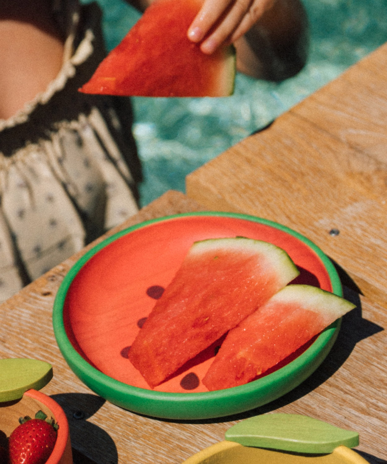 A close up of watermelon slices on the Oli & Carol Wally the watermelon wooden plate and spoon set available at Babipur.