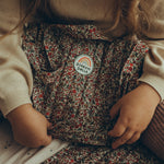 A closer look at the Olli Ella Carrie Convertible Changing Set in a floral  Garland print with a Dinkum Doll logo on the front.