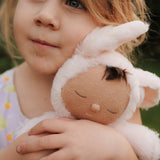 A close up of a girl holding the Olli Ella cozy dinkum bunny pip doll in pink showing the cute sleeping facial features. This fluffy toy doll is available at Babipur.
