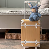 Olli Ella cozy dinkum bunny twiggy doll sitting on top of a Olli Ella suitcase in a bedroom. This fluffy toy doll is available at Babipur