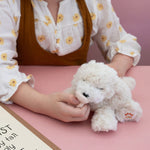 A child playing with the soft white Olli Ella Belle dinkum puppy.