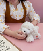 A child playing with the soft white Olli Ella Belle dinkum puppy.