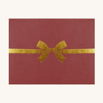 The packaging of the Olli Ella Dinkum Dolls Petal Carrier - Red Velvet. The box is a deep red colour, with a gold bow printed on the front.