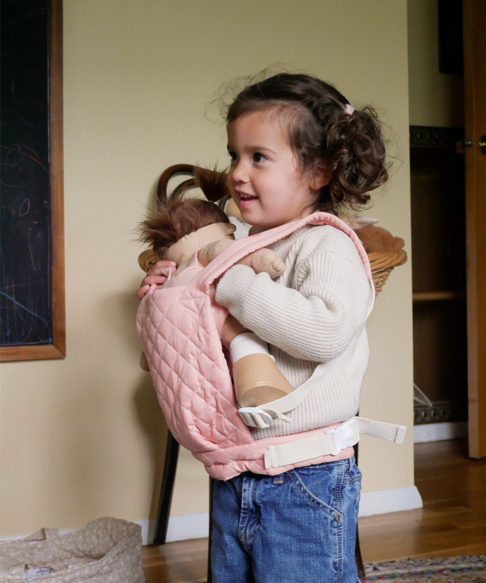 A child carrying a Olli Ella dinkum doll with the Olli Ella toy carrier in rose . This toy carrier is available at Babipur.