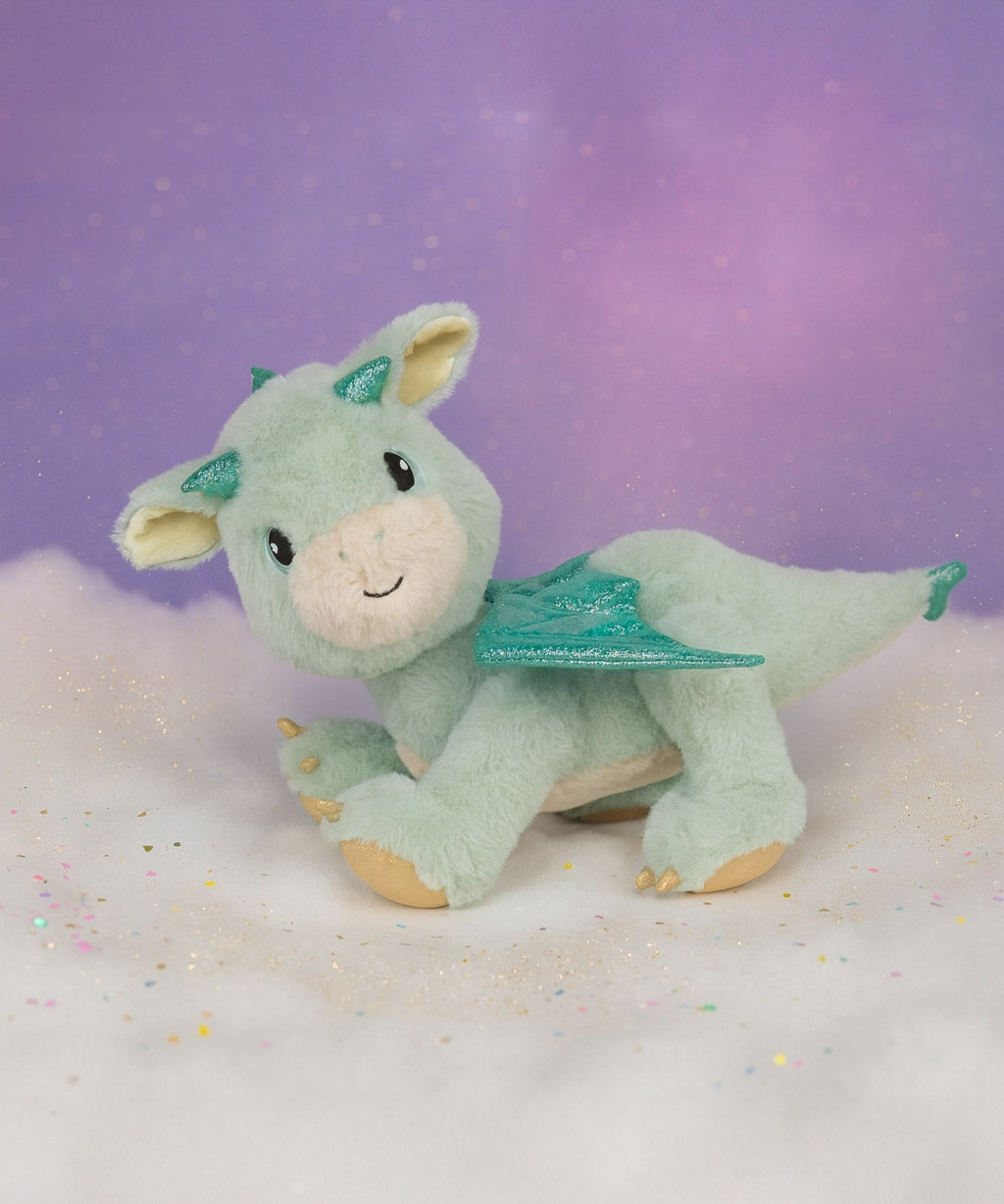 A Olli Ella dinkum dragon blaze doll standing on a fully cloud. This light green fluffy doll has movable limbs and features green glittery wings. This doll is available at Babipur.