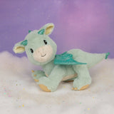 A Olli Ella dinkum dragon blaze doll standing on a fully cloud. This light green fluffy doll has movable limbs and features green glittery wings. This doll is available at Babipur.