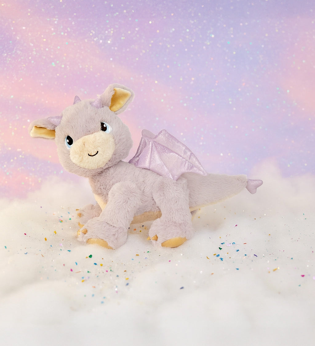 A Olli Ella dinkum dragon flare doll standing on a fully cloud. This light pink fluffy doll has movable limbs and features pink glittery wings. This doll is available at Babipur.