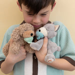 A child holding the grey and brown Olli Ella dinkum puppies