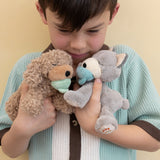 A child holding the grey and brown Olli Ella dinkum puppies
