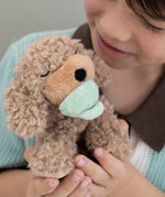 A child holding the soft and fluffy brown Benny Olli Ella dinkum doll
