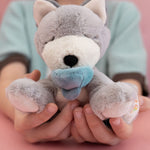 A child holding the soft grey and white Olli Ella dinkum puppy in their hands for scale